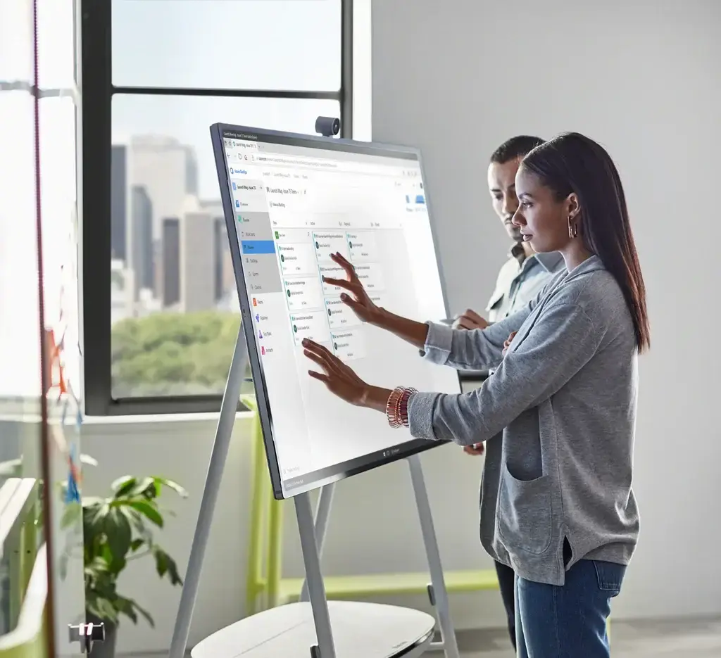 Dos colaboradores de trabajo haciendo uso de una herramienta de Surface Hub 2S en una oficina "Modernworkplace"